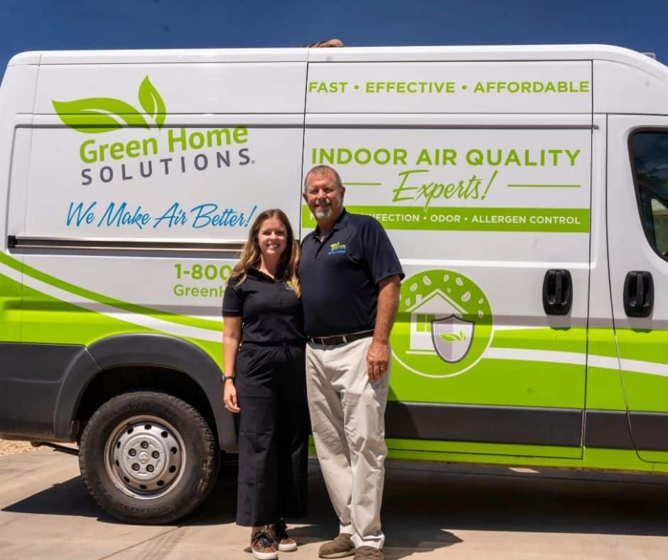 father and daughter in black polos standing in front of a white and green service van